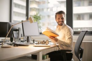 man in an office sitting at his desk smiling at someone off camera